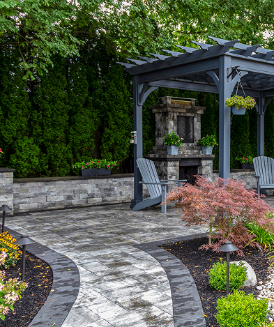 Courtyard garden with a blue-gray pergola, stone fountain centerpiece, two Adirondack chairs, a curved stone-paver path, and lush greenery.